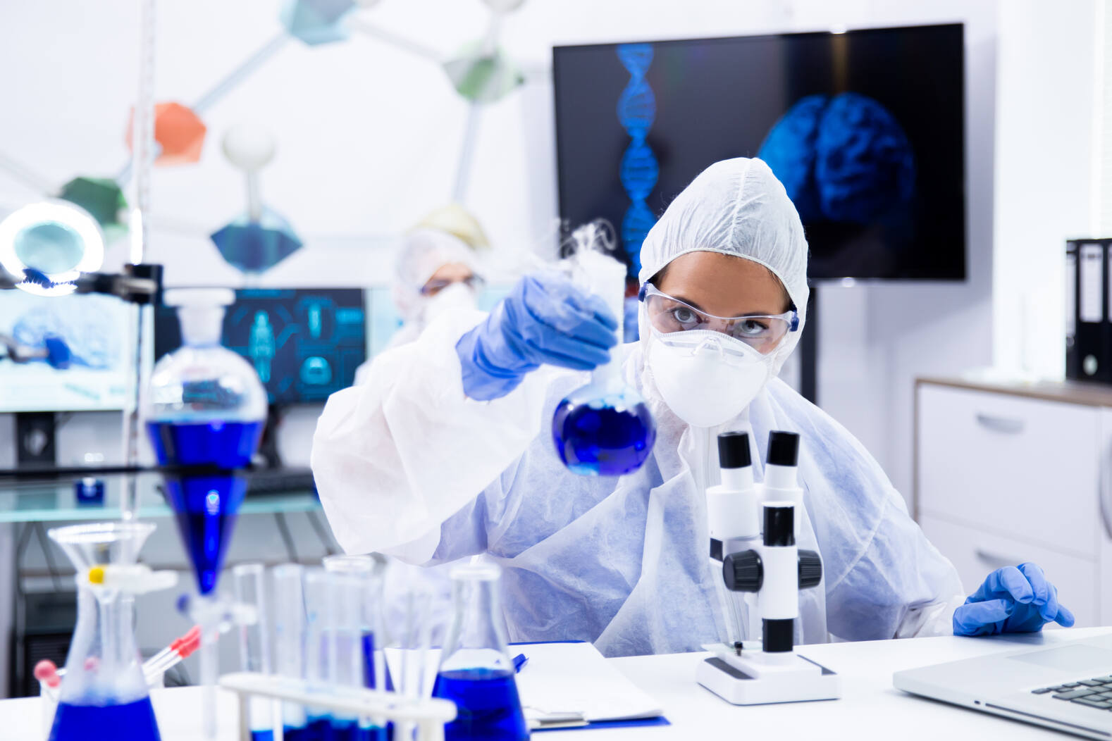 Scientist in protective equipment holding a test tube in a chemistry laboratory
