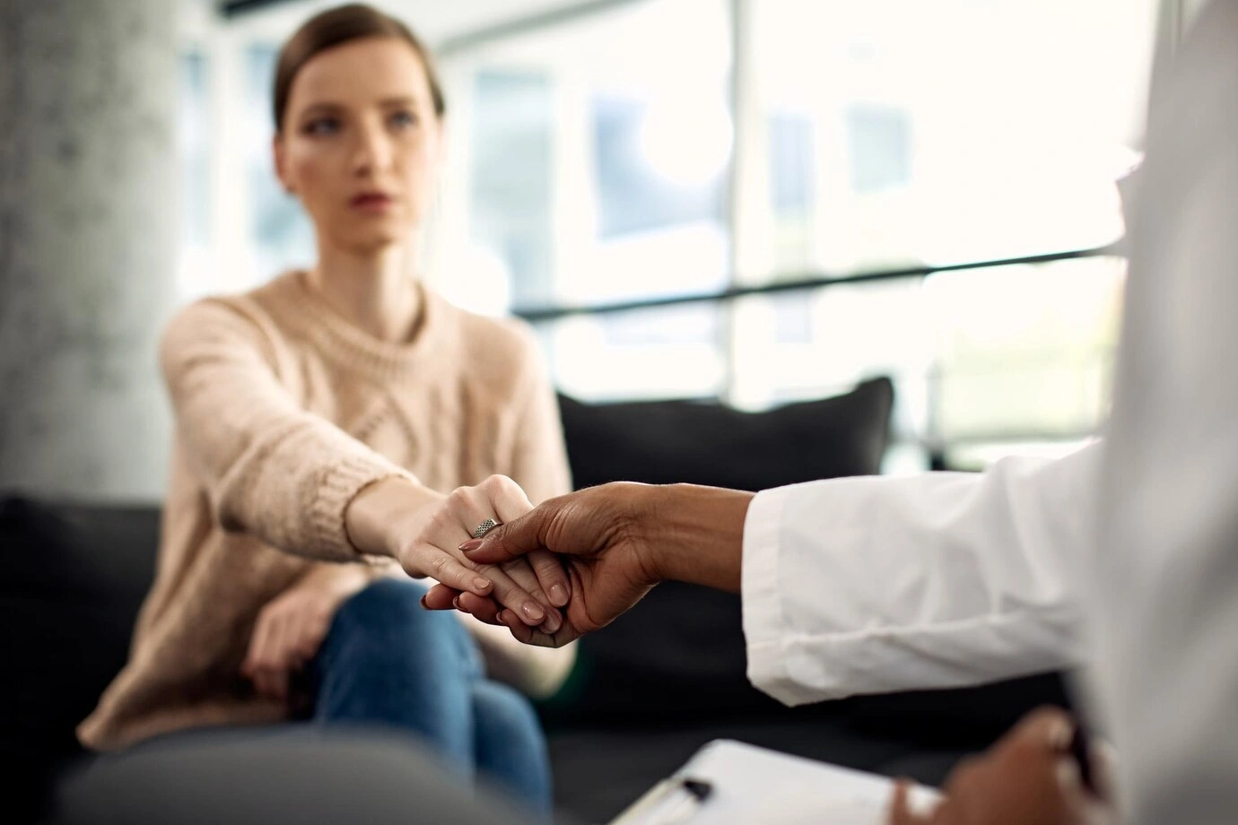 A clinician holding a patient's hands during a supportive consultation