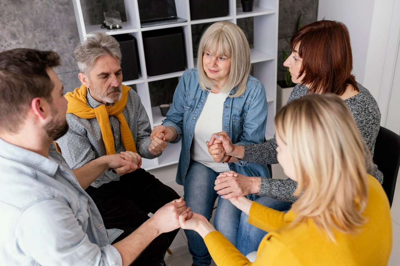 A support group session with participants' hands joined